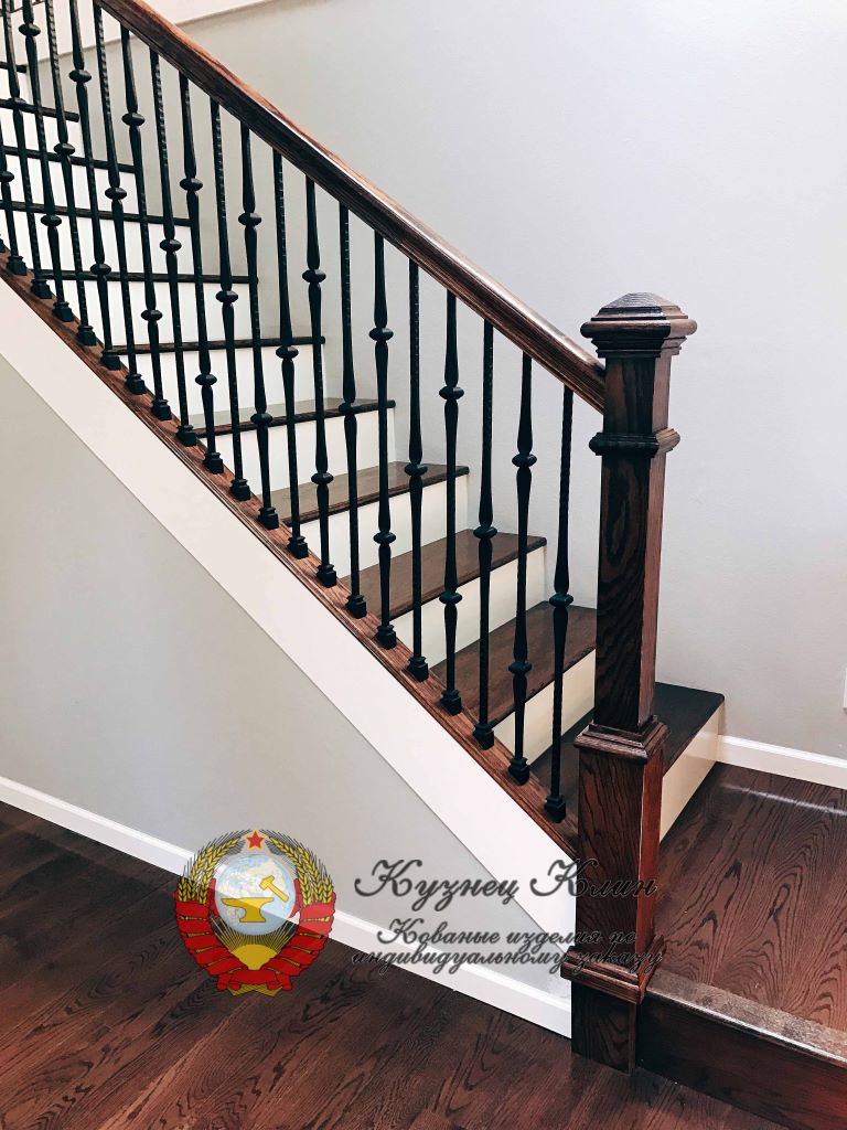 Лестница с коваными балясинами и деревянным заходным столбом